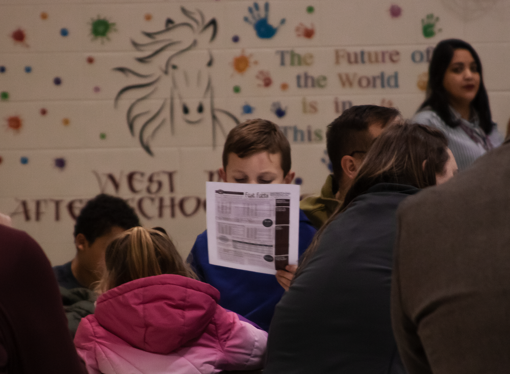 A young boy reads an information sheet on the Columbus Public Schools bond referendum during a public event at West Park Elementary.